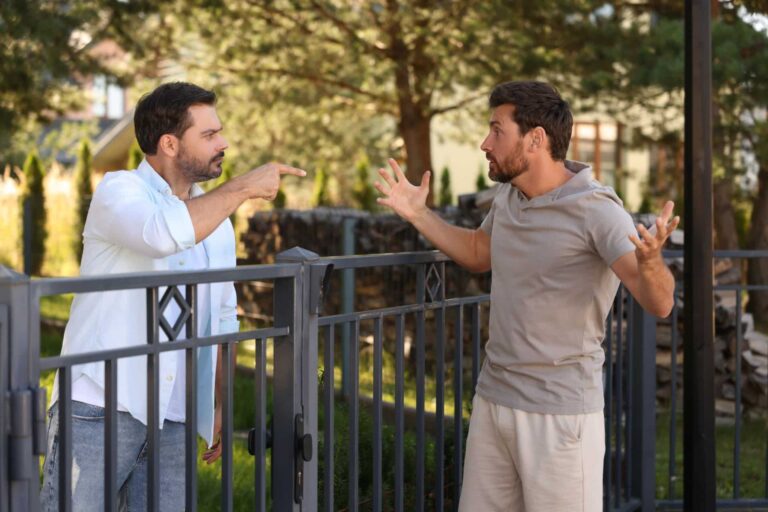 angry neighbours having argument near fence outdoors
