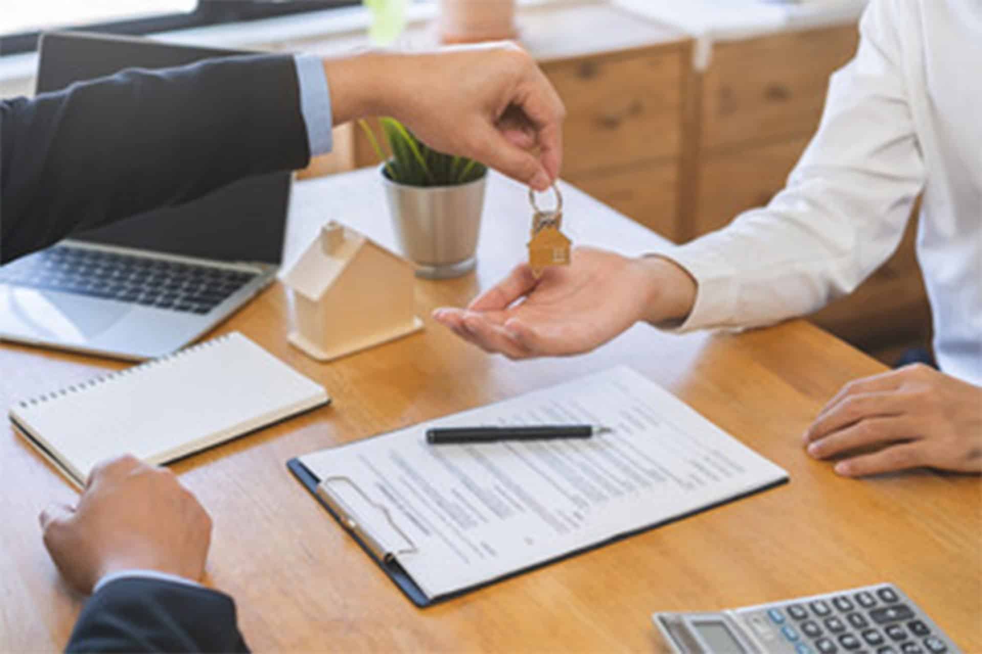 man is handing piece paper another person who is holding key their hand
